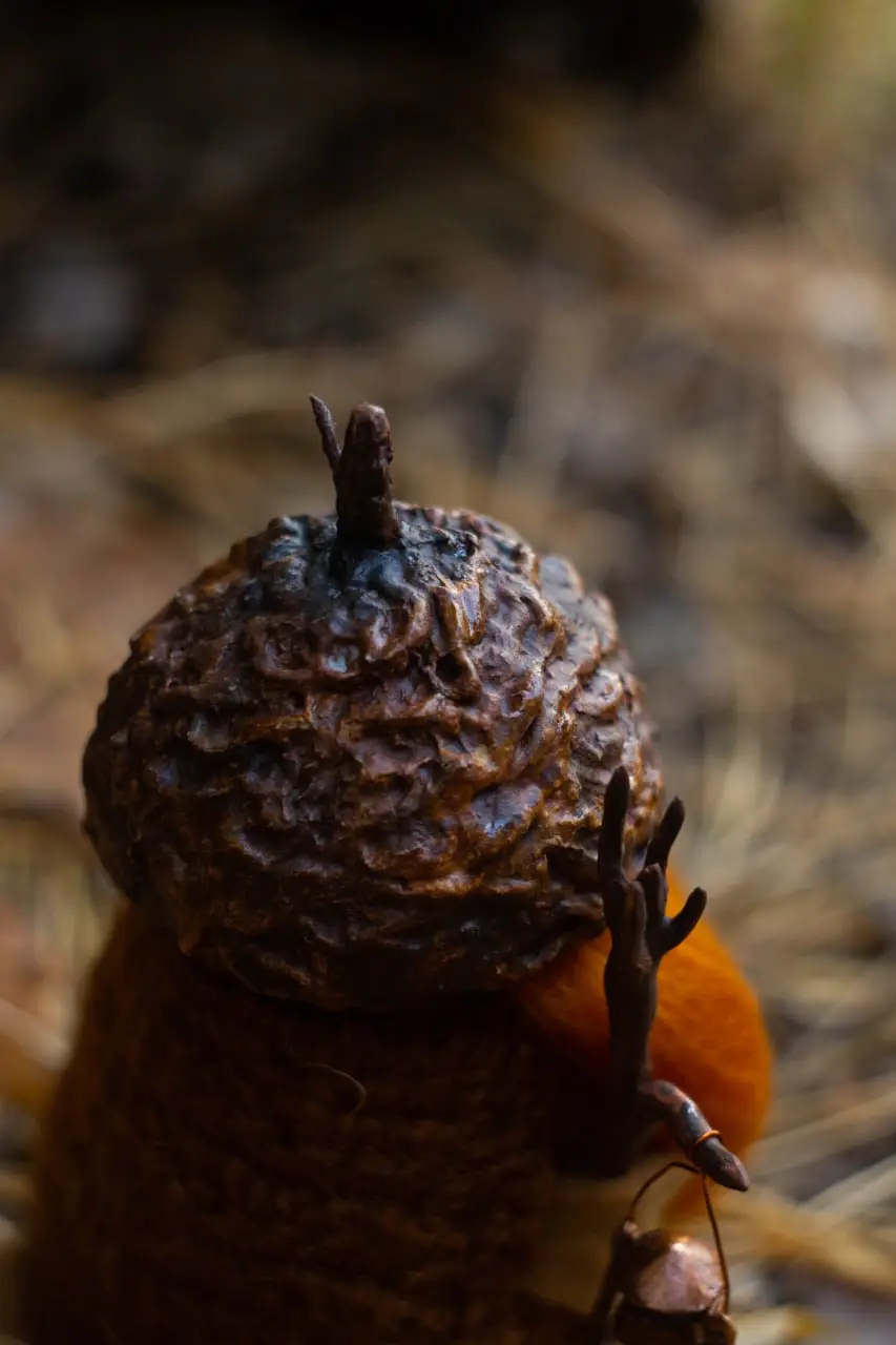 Decorative collectible gnome in knitted vest, brooch and acorn hat