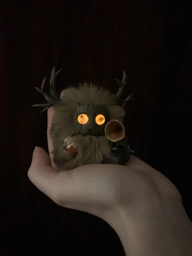 Nostalgia fluffy — amber eyes glowing in darkness, held in hand