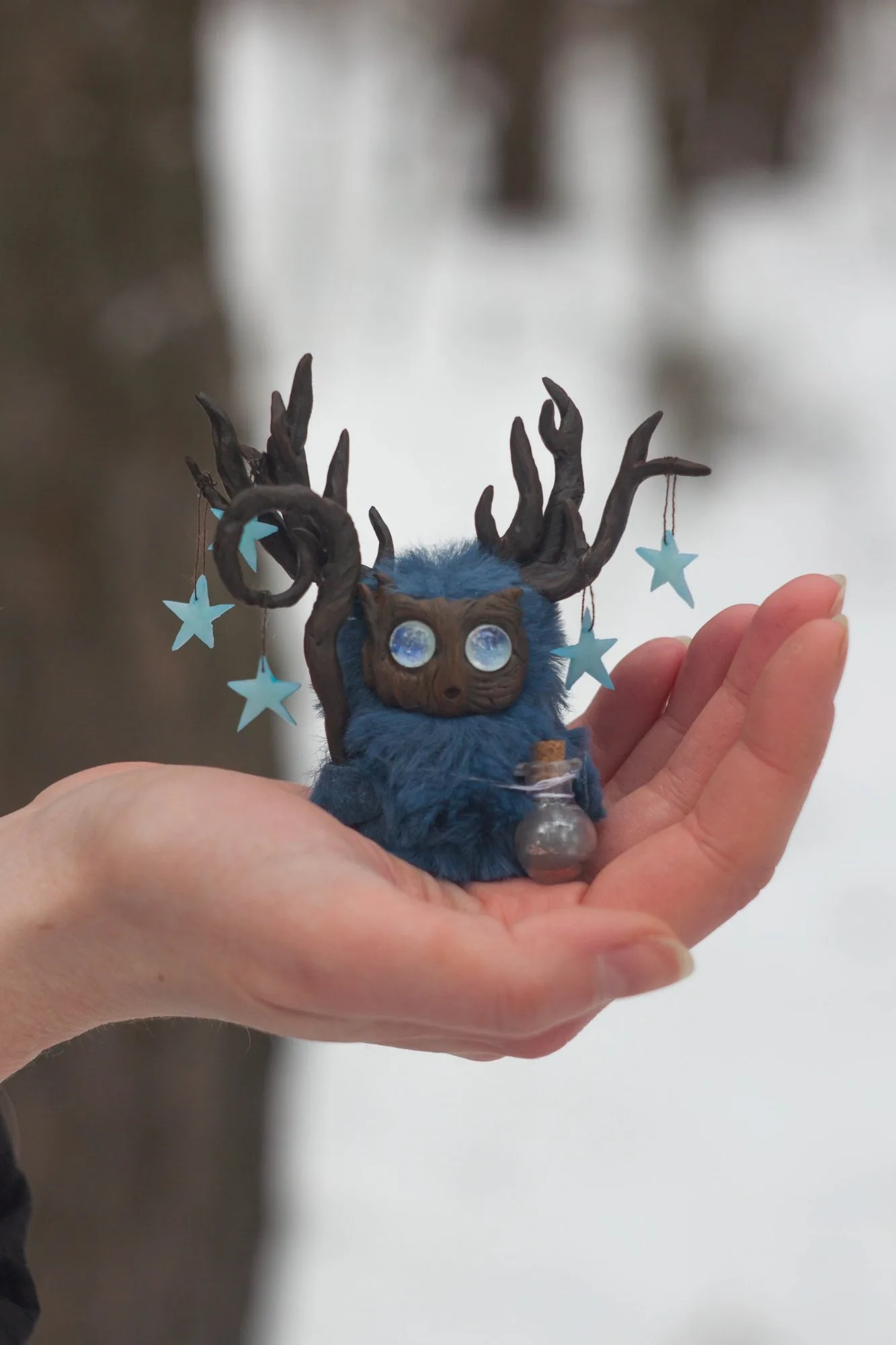Polaris fluffy — held in hand showing size, blue wool and star pendants