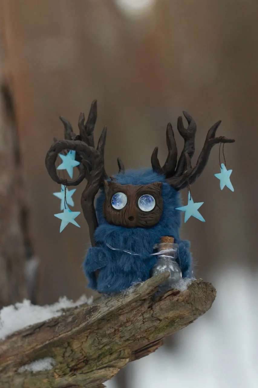 Polaris — handmade blue wool Fluffy creature with branching antlers, glowing star eyes and tiny star pendants, sitting on a snowy branch | Gnomenlands