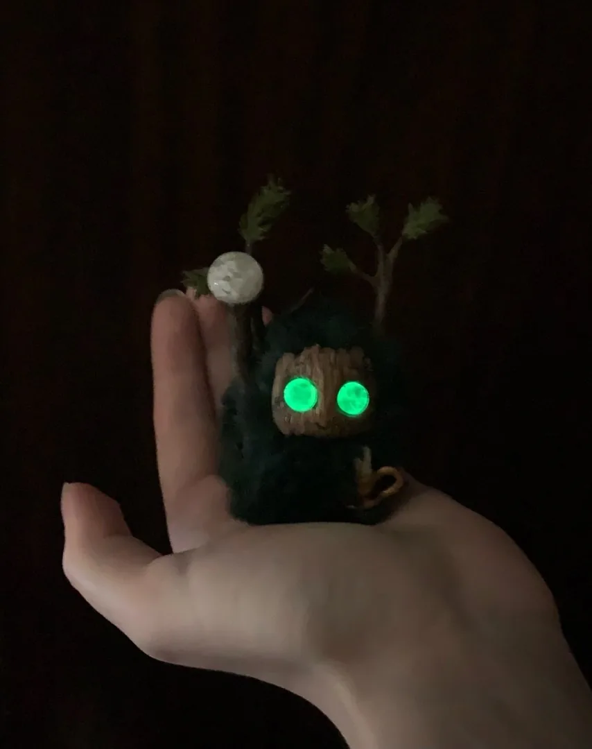 Snowy Forest fluffy — bright green eyes glowing in darkness, held in hand with snowball staff visible