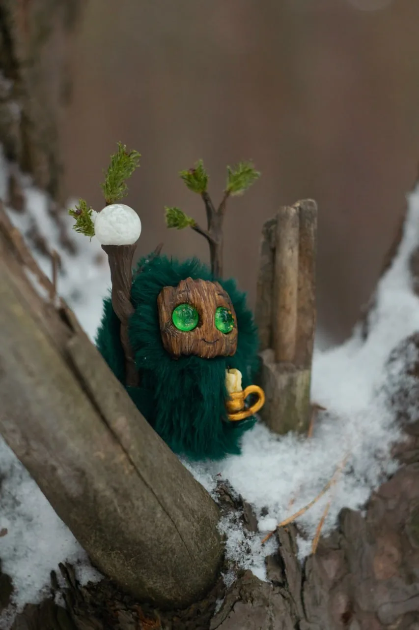 Snowy Forest fluffy — side view peeking from snow-dusted tree fork, dark green coat