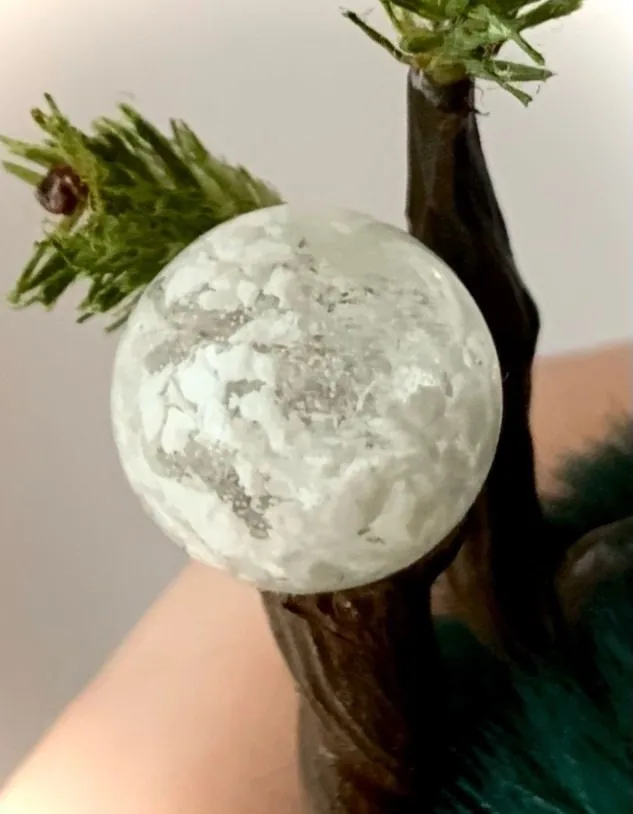 Snowy Forest fluffy — close-up of snow-globe staff ball with silver swirl details atop fir-branch handle