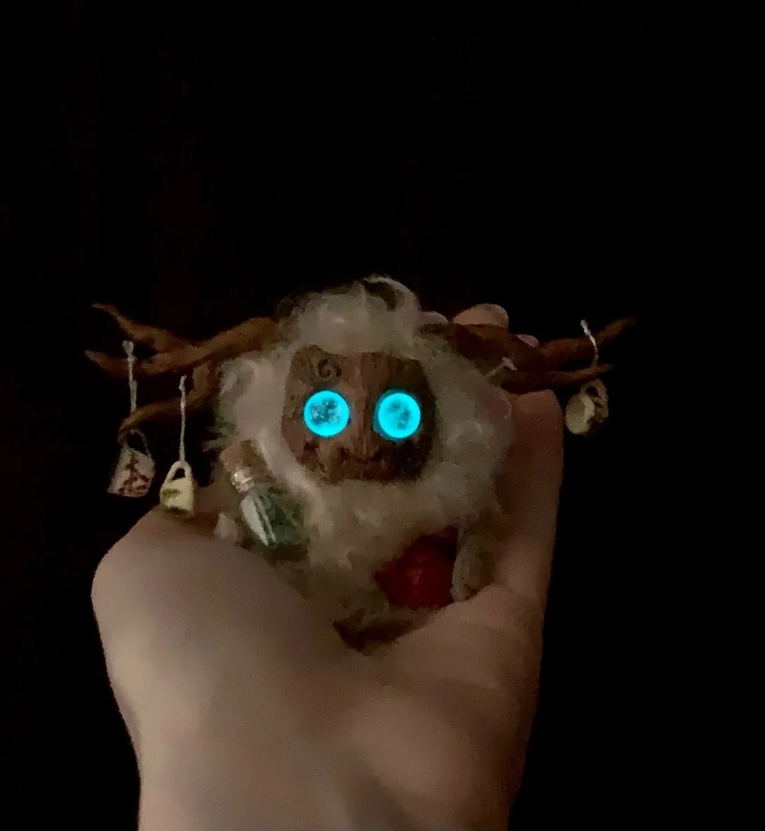 Yeti fluffy — turquoise eyes glowing in darkness, held in hand