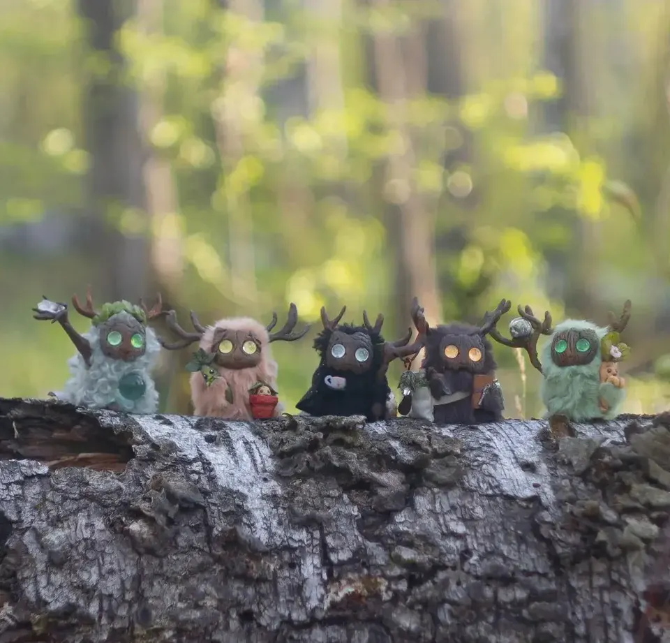 Five handmade Fluffy forest creatures perched on a mossy log in a spring forest — Gnomenlands collection Wild Garden, April 2025