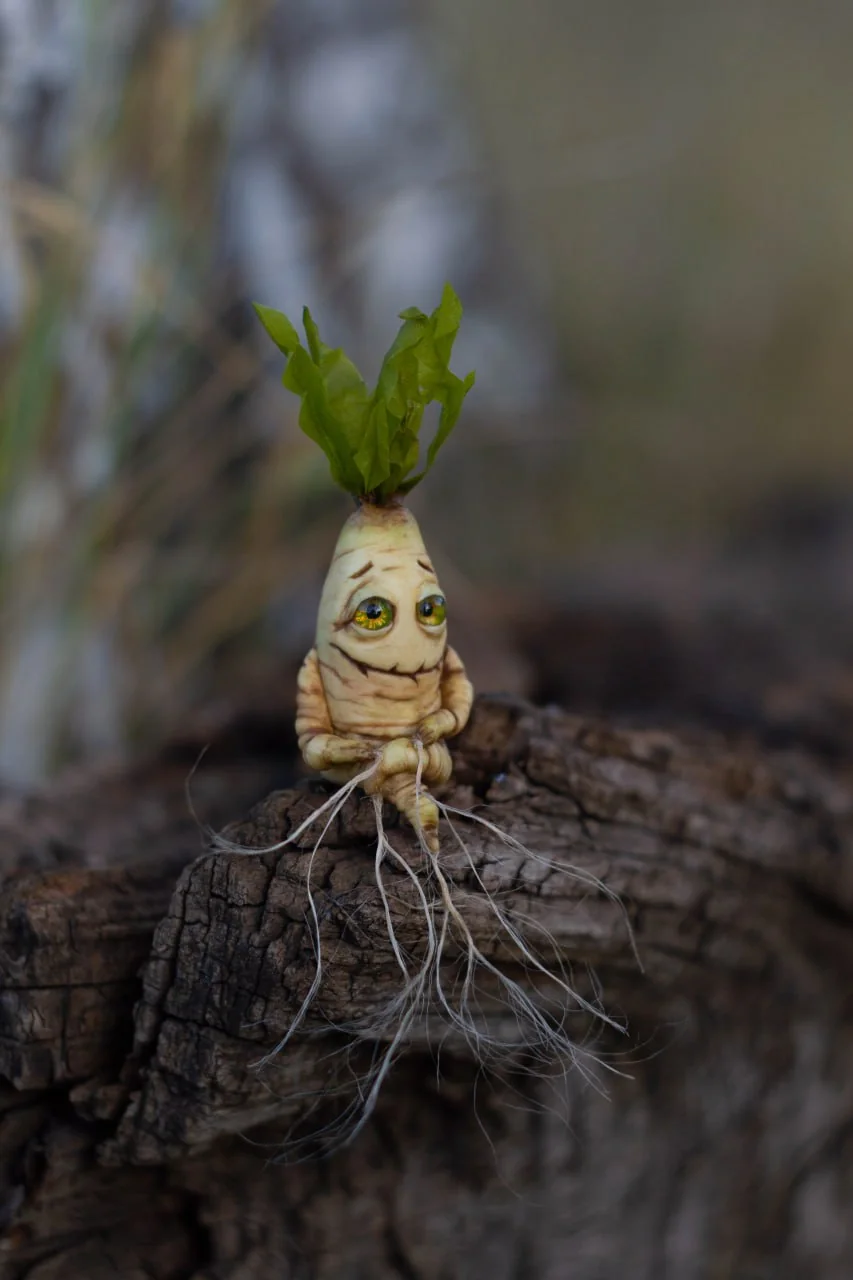 Handmade mandrake root figurine front view — sitting on log with long root tendrils