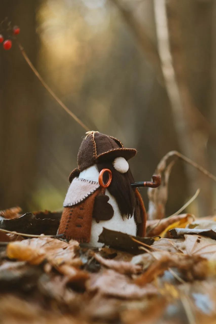 Consulting detective gnome among autumn leaves — side angle