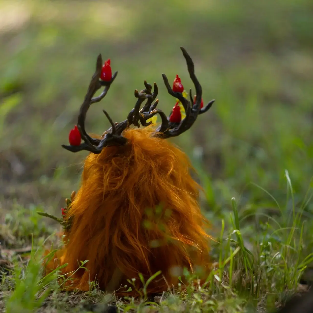 Wood Spirit Litha Flame — side view on grass, long orange faux fur with red fire spirits on dark antlers, handmade fantasy sculpture