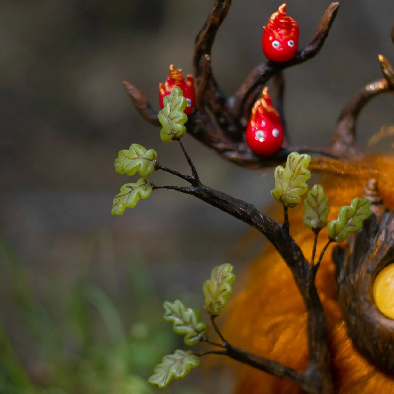 Fire spirit close-up on Wood Spirit Litha Flame — detailed polymer clay sculpt with expressive tiny eyes and gold-tipped flame, artisan miniature collectible