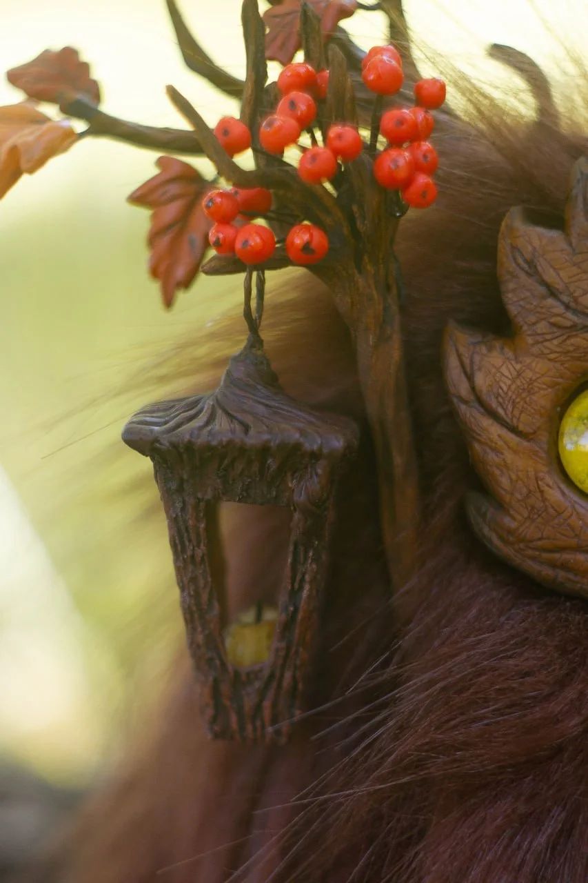Wood Spirit Mabon Rustle — rear view on log with autumn leaves, deep burgundy faux fur and antlers bearing oak leaves and rowan, handmade fantasy collectible sculpture