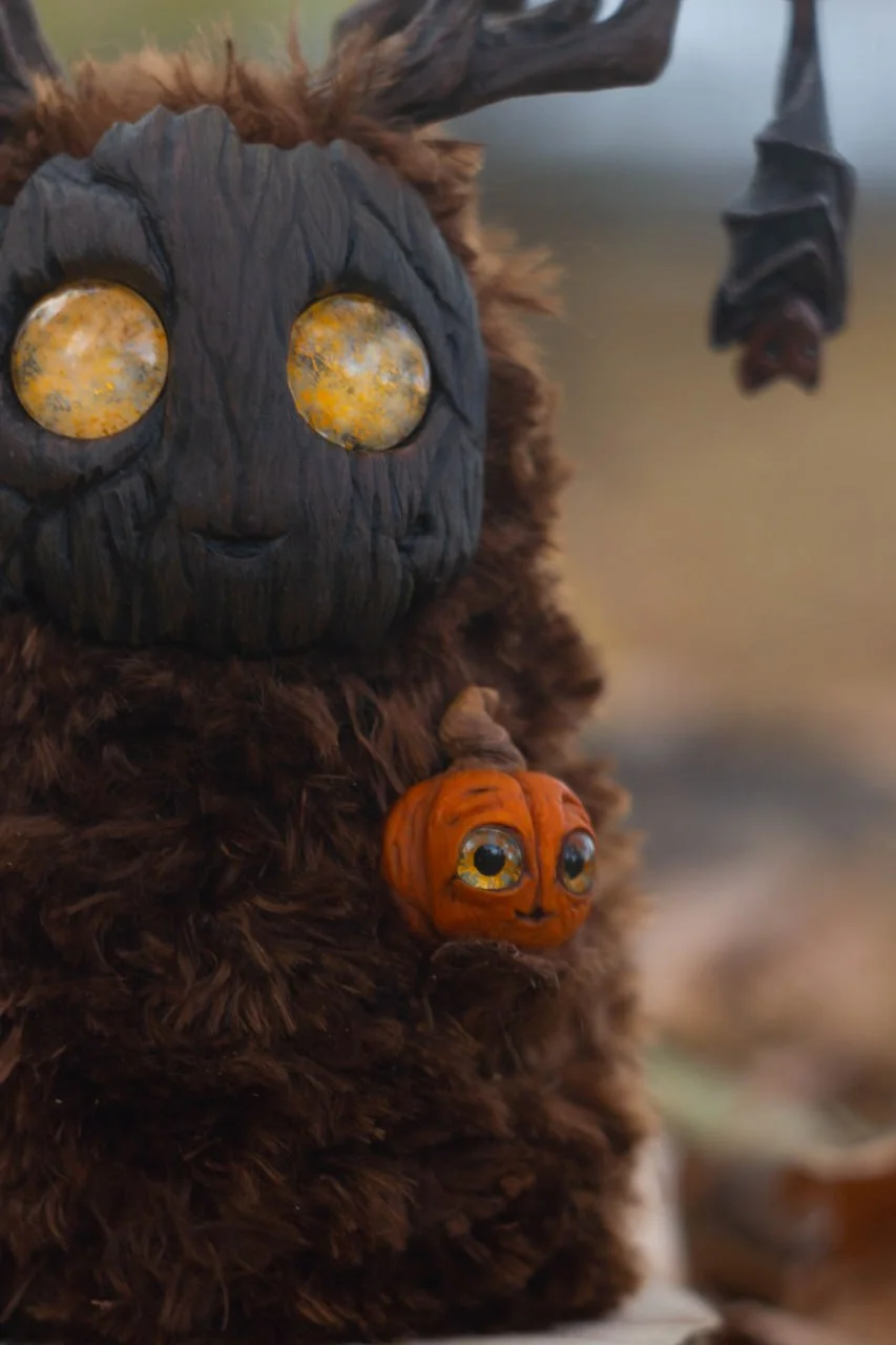 Wood Spirit Samhain Whisper — rear view on autumn log, rich dark faux fur with branching antlers, handmade fantasy collectible sculpture