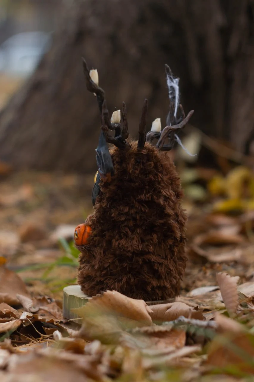 Wood Spirit Samhain Whisper face close-up — handcrafted wooden bark-textured mask with glowing amber glass eyes, artisan Halloween figurine